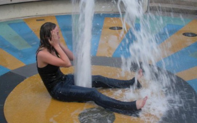 girl sitting over a gushing fountain that makes her look like she is squirting