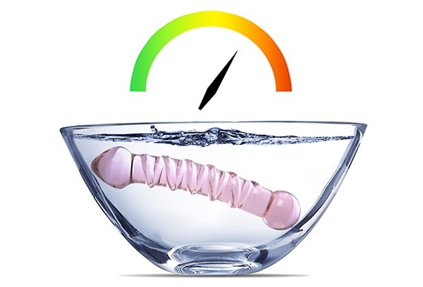 Glass dildo in a bowl of water with temperature gauge graphic above it