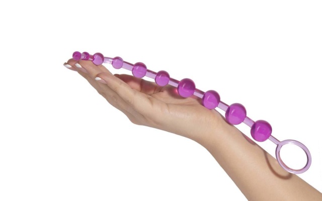 Luxurious pink anal beads resting in hand of mwoman