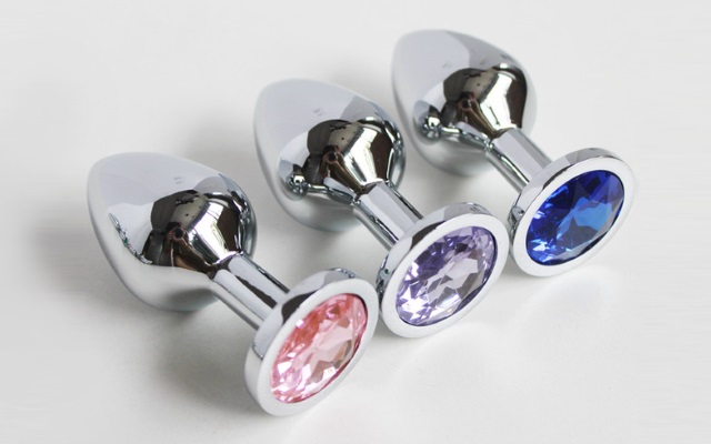 Blue, pink and purple stainless steel butt plugs laying next to each other